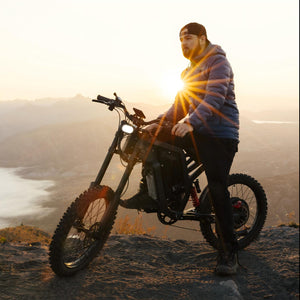 Rider on a Freego electric dirt bike overlooking a mountain landscape at sunrise, capturing the spirit of off-road adventure.
