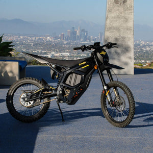 Freego Nova5 electric dirt bike parked with panoramic city skyline and mountain backdrop, side view product photo