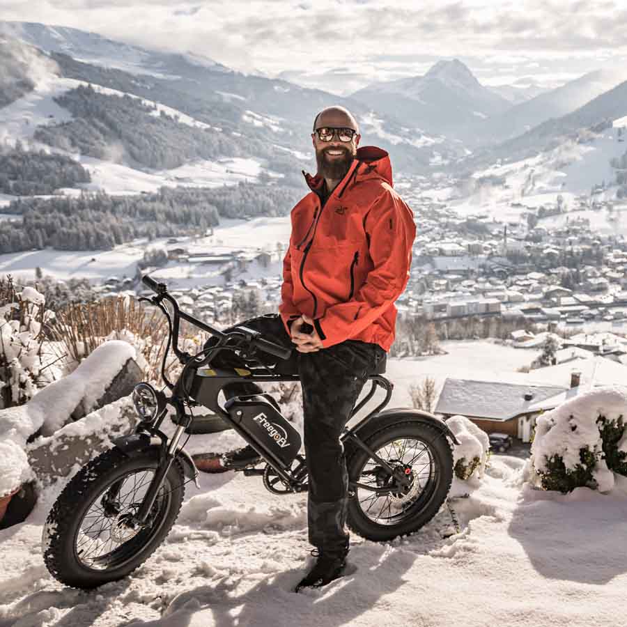 A man sitting on a Freego DK200 fat tire ebike surrounded by snowy mountains 
