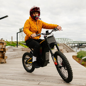 Freego Nova 4 electric dirt bike front riding view on wooden boardwalk