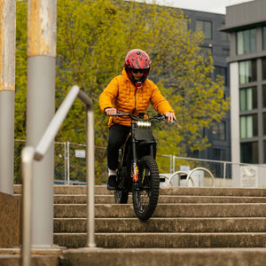 Freego Nova 4 electric dirt bike riding down steps action in urban park