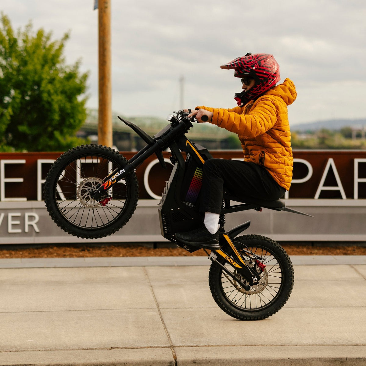 Freego Nova 4 electric dirt bike performing wheelie riding action on pavement