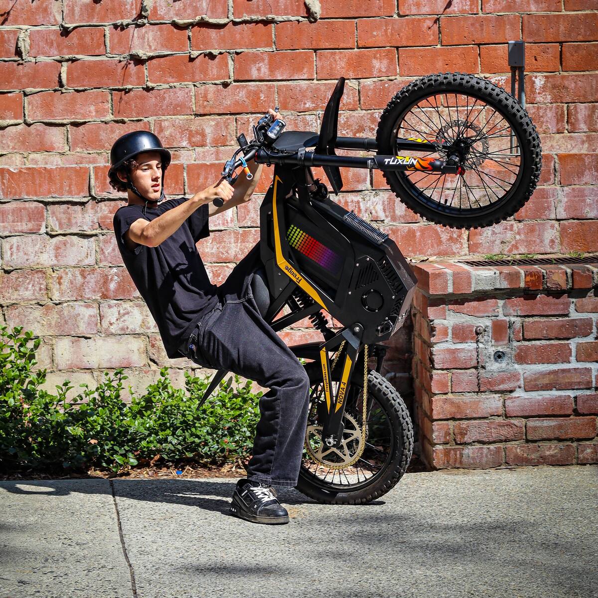 Freego Nova 4 electric bike wheelie action shot against brick wall