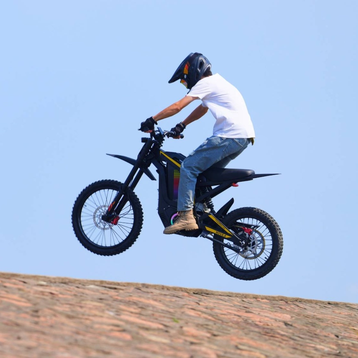 Rider airborne jumping on Freego Nova4 electric dirt bike against clear blue sky