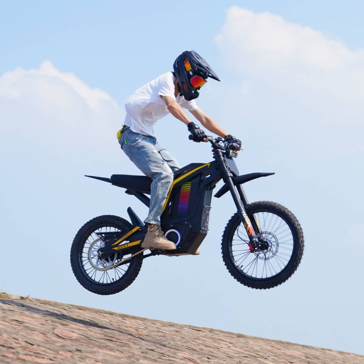 Rider jumping on Freego Nova4 electric dirt bike with clear blue sky background